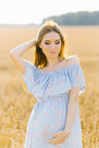 Giovane donna incinta in vestito blu che si rilassa fuori nella natura