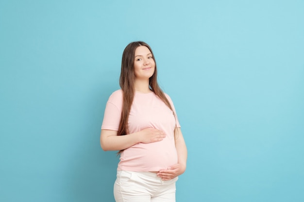 Giovane donna incinta isolata sull'azzurro