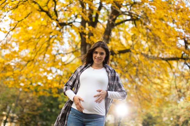 Giovane donna incinta nel parco autunnale