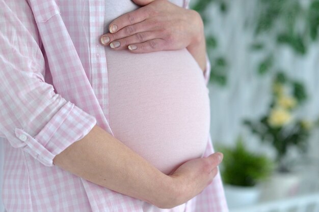 Giovane donna incinta, tenendo la pancia da vicino