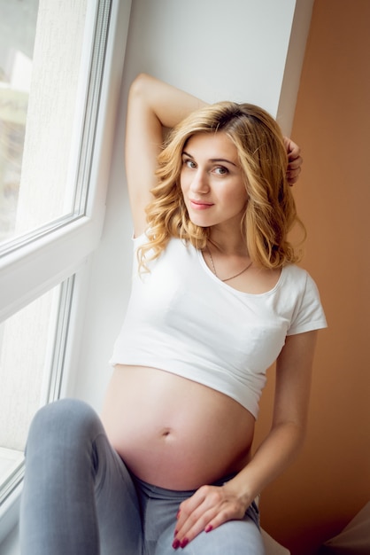 Giovane donna incinta vicino alla finestra