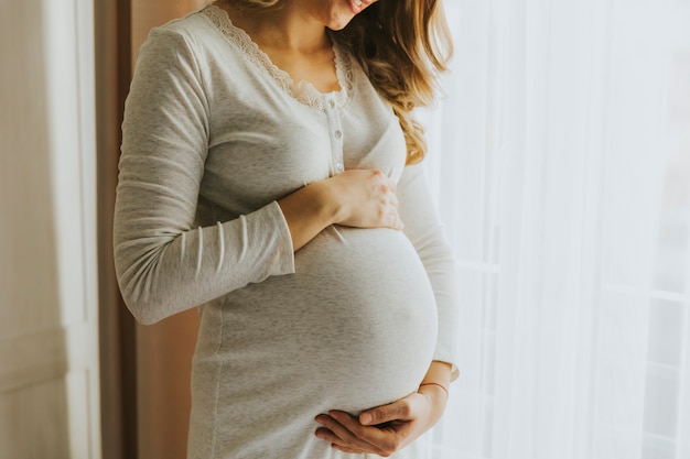 Giovane donna incinta vicino alla finestra