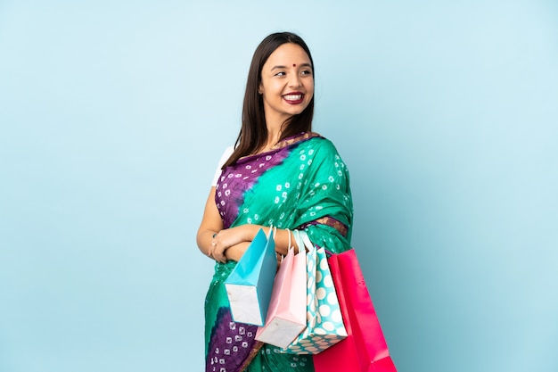 Giovane donna indiana con i sacchetti della spesa con le armi attraversate e felici