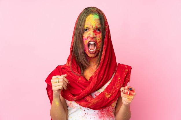 Giovane donna indiana con le polveri colorate di holi sul suo viso sulla parete rosa frustrata da una brutta situazione