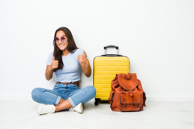 Giovane donna indiana di razza mista pronta a partire per viaggiare sollevando entrambi i pollici, sorridendo e fiducioso.