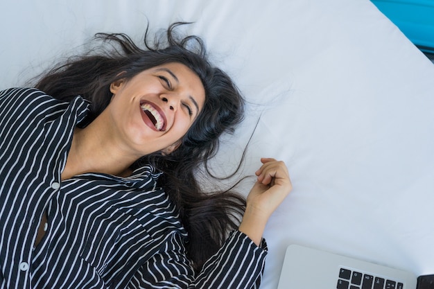 Giovane donna indiana felice e sorridente a letto