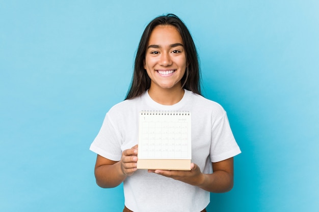 Giovane donna indiana felice giudicando un calendario isolato