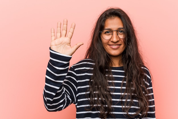 Giovane donna indiana intellettuale sorridente mostrando il numero cinque con le dita.