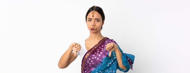 Giovane donna indiana isolata su bianco che mostra il pollice verso il basso con due mani