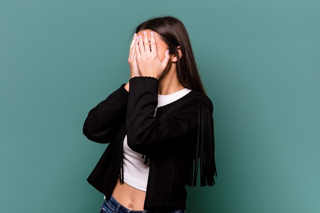 Giovane donna indiana isolata su sfondo blu paura che copre gli occhi con le mani.