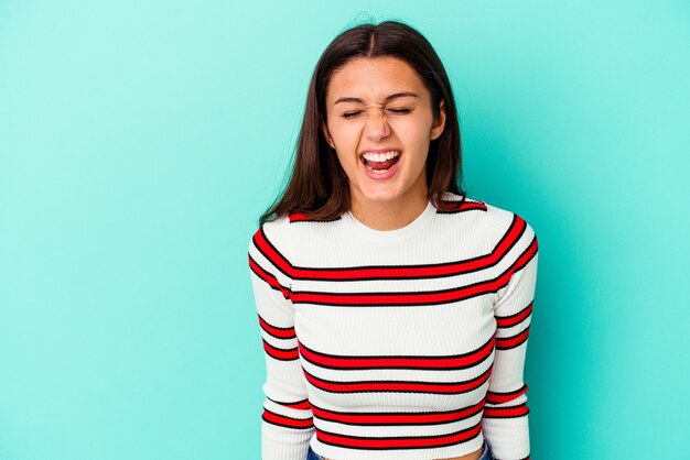 Giovane donna indiana isolata sull'azzurro che grida molto arrabbiato, concetto di rabbia, frustrato.