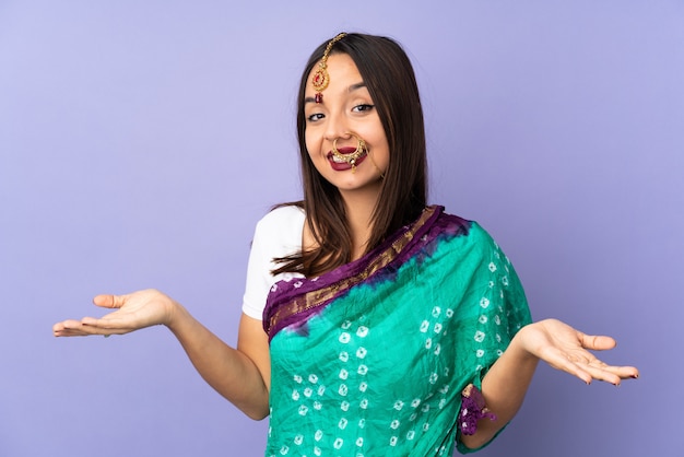 Giovane donna indiana isolata sulla parete viola felice e sorridente