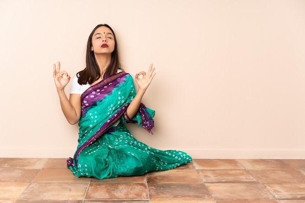 Giovane donna indiana seduta sul pavimento in posa zen