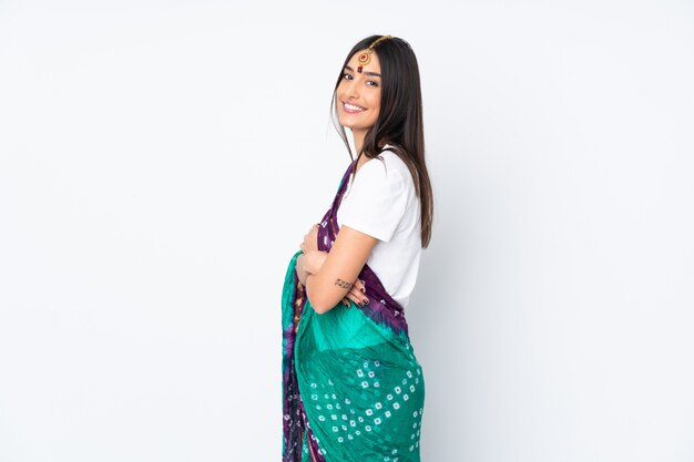 Giovane donna indiana sul muro bianco con le braccia incrociate e guardando avanti