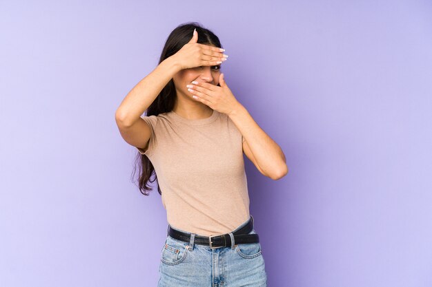 Giovane donna indiana sulla parete viola che lampeggia tramite le dita