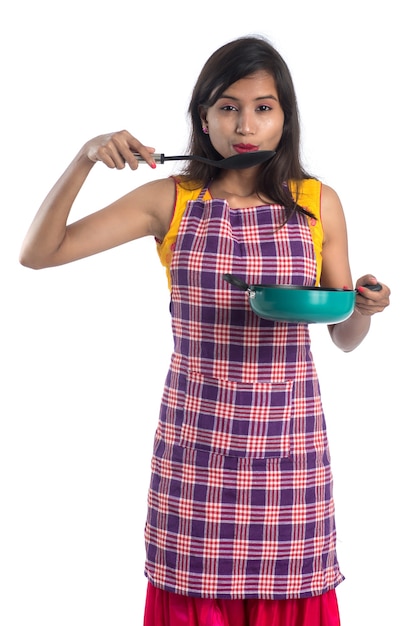 Giovane donna indiana tenendo un utensile da cucina (cucchiaio, stapola, mestolo e padella, ecc.)