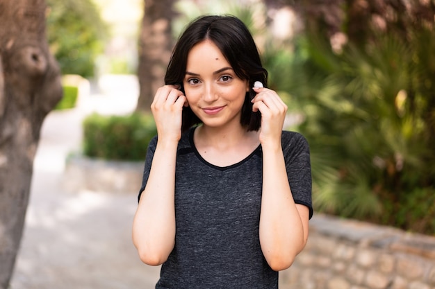 Giovane donna indoeuropea sport ascoltando musica all'aperto in un parco