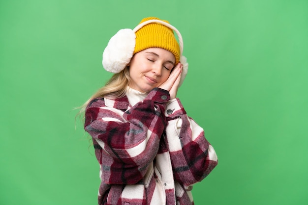 Giovane donna inglese che indossa manicotti invernali su sfondo isolato facendo il gesto del sonno in espressione dorable