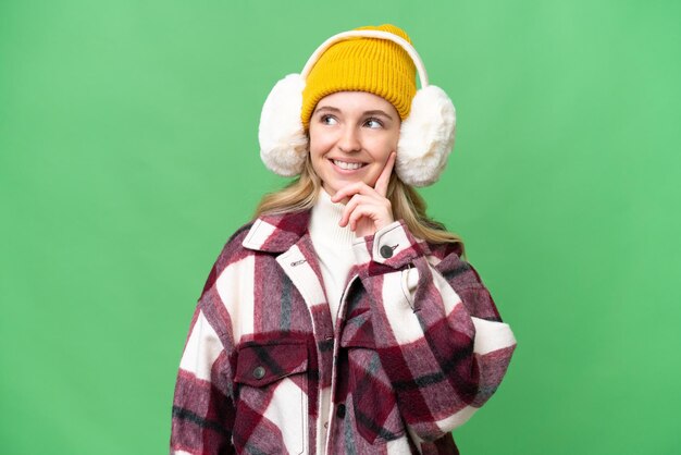 Giovane donna inglese che indossa manicotti invernali su sfondo isolato pensando un'idea guardando in alto