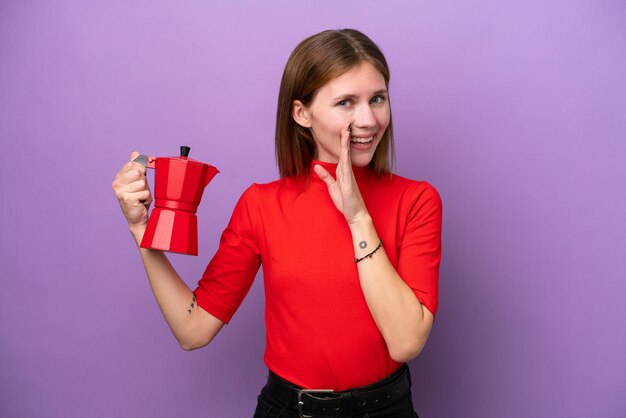 Giovane donna inglese che tiene caffettiera isolata su sfondo viola sussurra qualcosa