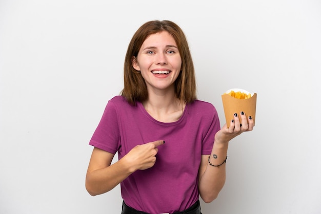 Giovane donna inglese che tiene patatine fritte isolate su sfondo bianco con espressione facciale a sorpresa