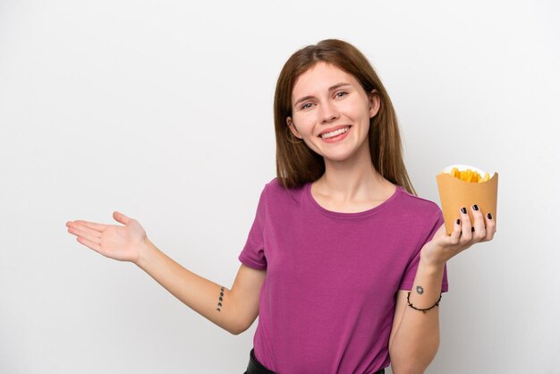 Giovane donna inglese che tiene patatine fritte isolate su sfondo bianco estendendo le mani di lato per invitare a venire