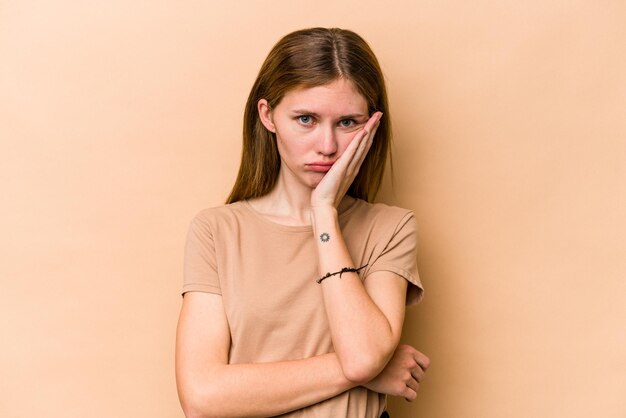 Giovane donna inglese isolata su sfondo beige che si annoia affaticata e ha bisogno di una giornata di relax