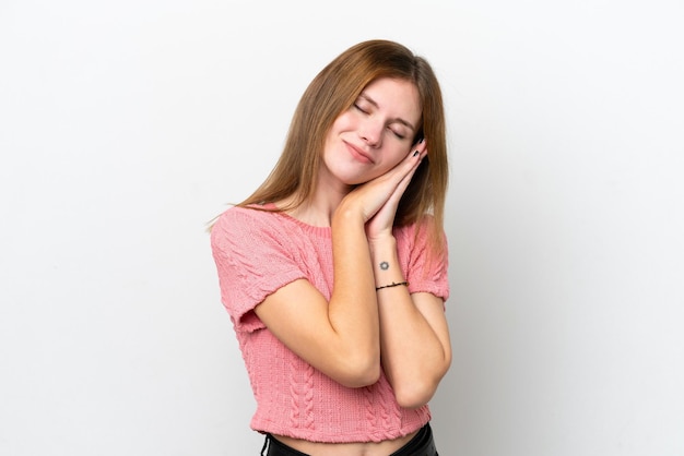 Giovane donna inglese isolata su sfondo bianco che fa il gesto del sonno in un'espressione adorabile