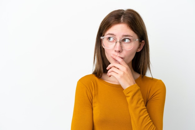 Giovane donna inglese isolata su sfondo bianco Con gli occhiali e con dei dubbi