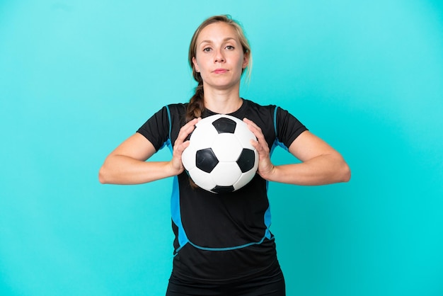 Giovane donna inglese isolata su sfondo blu con pallone da calcio