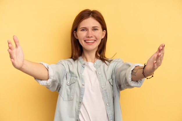 Giovane donna inglese isolata su sfondo giallo che celebra una vittoria o un successo è sorpreso e scioccato