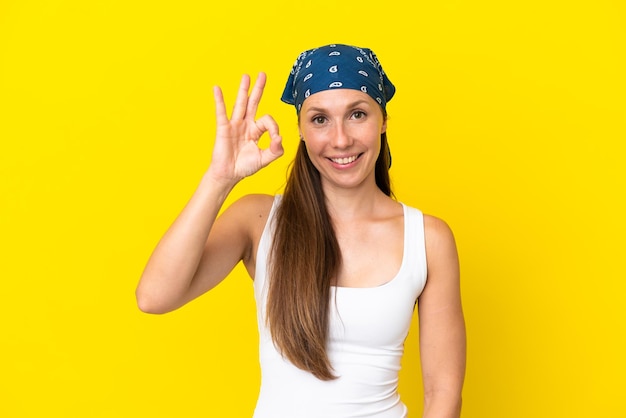 Giovane donna inglese isolata su sfondo giallo che mostra segno ok con le dita
