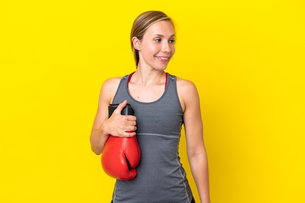 Giovane donna inglese isolata su sfondo giallo con guantoni da boxe