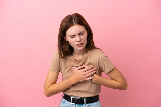 Giovane donna inglese isolata su sfondo rosa con un dolore al cuore