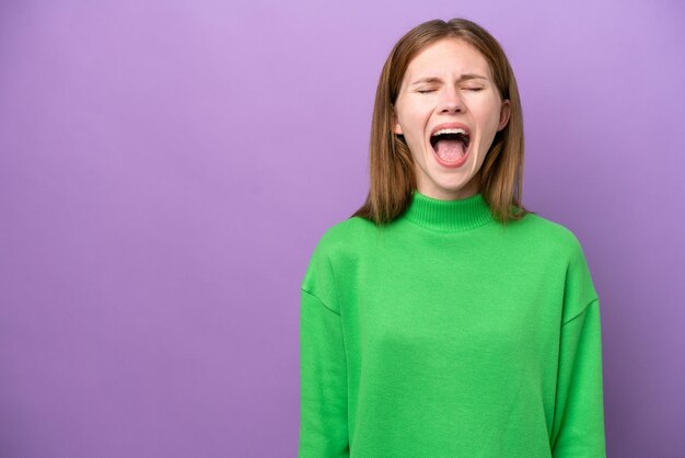 Giovane donna inglese isolata su sfondo viola che grida davanti con la bocca spalancata