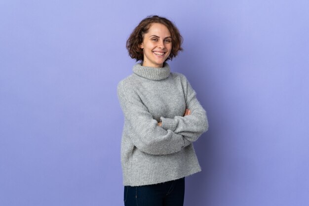 Giovane donna inglese isolata sulla parete viola con le braccia incrociate e guardando avanti