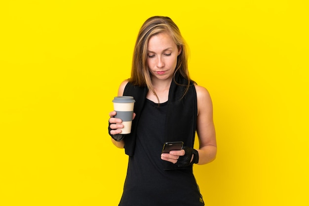 Giovane donna inglese sportiva isolata su sfondo bianco che tiene il caffè da portare via e un cellulare