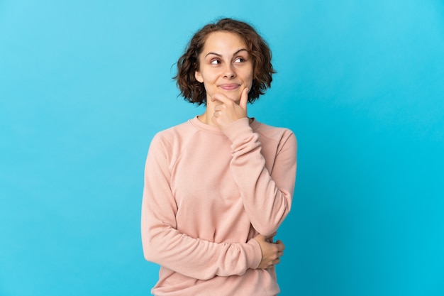 Giovane donna inglese sull'azzurro che pensa un'idea mentre osserva in su