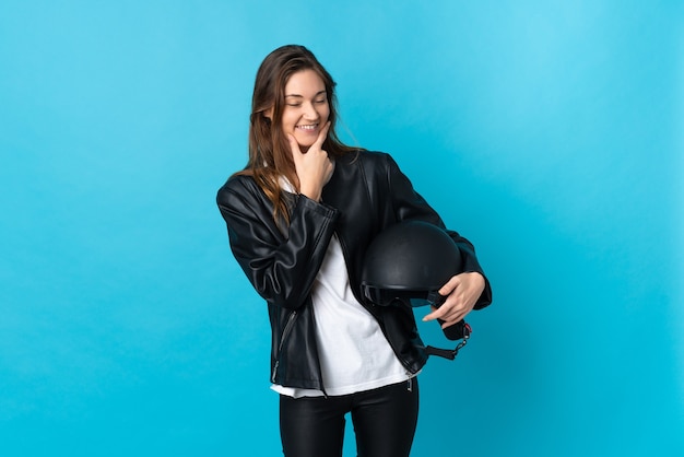 Giovane donna Irlanda in possesso di un casco da motociclista isolato su sfondo blu felice e sorridente