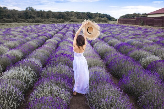 Giovane donna irriconoscibile che sta sul giacimento della lavanda. Signora d'estate