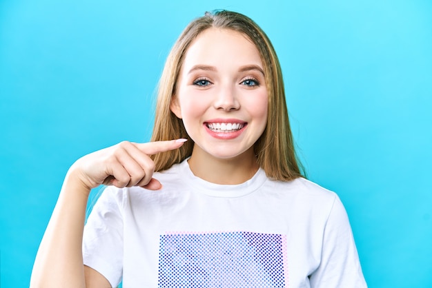 giovane donna isolata su sfondo blu, mostrando i suoi denti