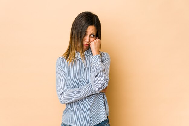 Giovane donna isolata sul beige che si sente triste e pensierosa, guardando lo spazio della copia.