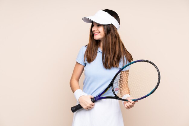 Giovane donna isolata sulla parete beige che gioca a tennis