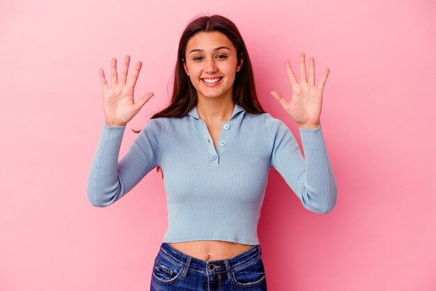 Giovane donna isolata sulla parete rosa che mostra il numero dieci con le mani