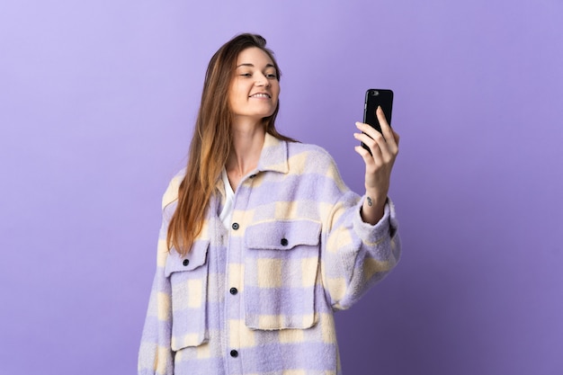 Giovane donna isolata sulla parete viola che fa un selfie con il telefono cellulare