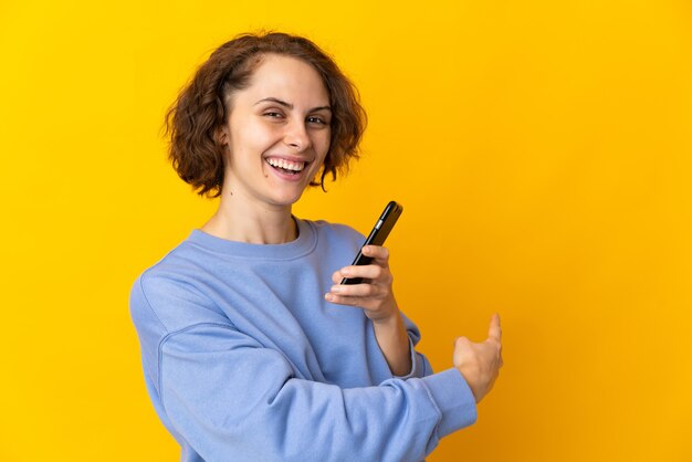 Giovane donna isolata utilizzando il telefono cellulare e indicando indietro