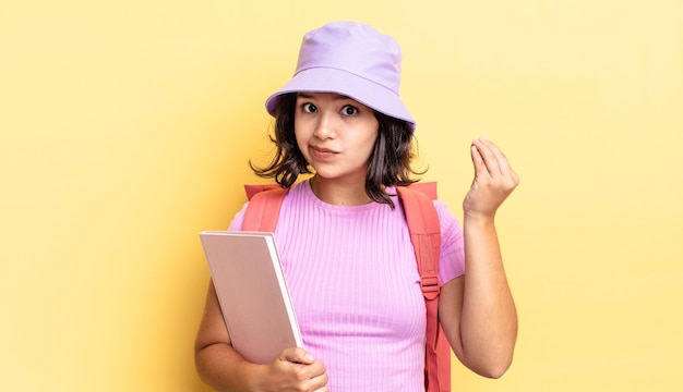 Giovane donna ispanica che fa un gesto capice o denaro, dicendoti di pagare. torna al concetto di scuola