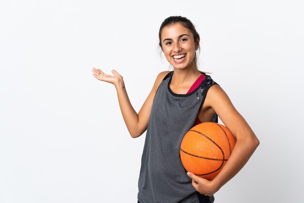 Giovane donna ispanica che gioca a basket su bianco isolato che estende le mani a lato per invitare a venire