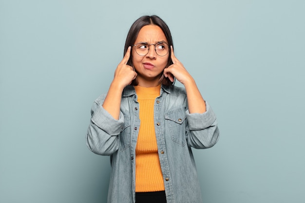 Giovane donna ispanica che guarda concentrata e pensa intensamente a un'idea, immaginando una soluzione a una sfida o un problema