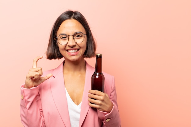 Giovane donna ispanica che incornicia o delinea il proprio sorriso con entrambe le mani, guardando positivo e felice, concetto di benessere